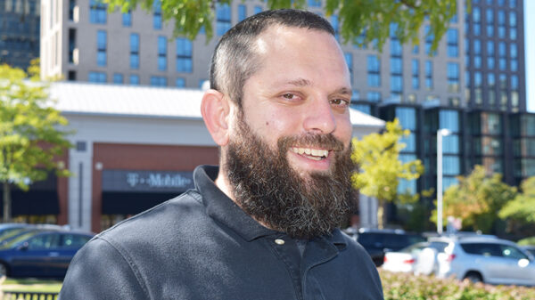 Matt Starr, NV Rides volunteer standing with a building and green trees in the backdrop. He's happy because transportation for seniors is now solved!