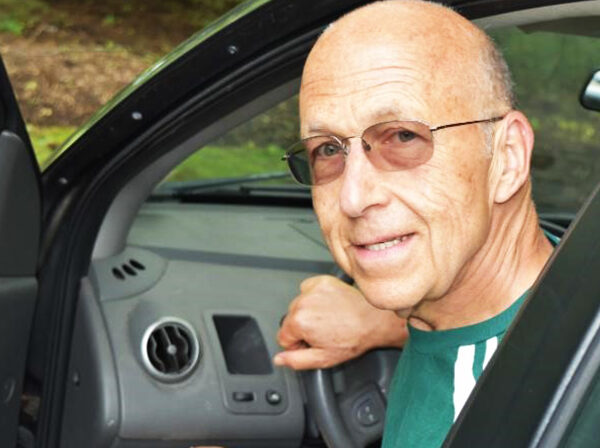 Volunteer driver, Mark Turco smiles as he exits his car. He is a volunteer driver to a program that provides transportation to aging adults in the Northern Virginia area. He's happy because transportation for seniors is now solved!