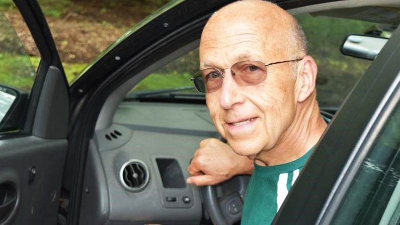 Volunteer driver, Mark Turco smiles as he exits his car. He is a volunteer driver to a program that provides transportation to aging adults in the Northern Virginia area. He's happy because transportation for seniors is now solved!